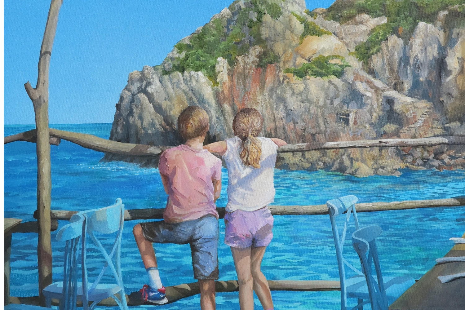 Two people standing on a dock overlooking a rocky coastline with clear blue water.